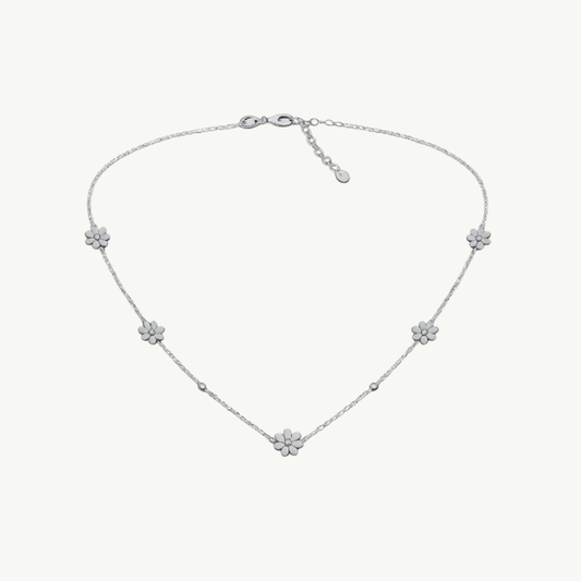 A delicate silver chain necklace featuring five small flower motifs spaced along the chain, displayed on a clean off-white background.