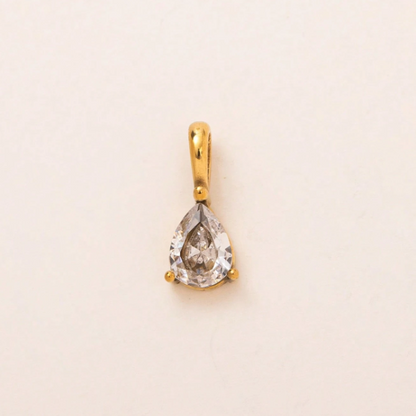A pear-shaped clear gemstone pendant set in a gold bezel with a bail, centered on a plain off-white background.
