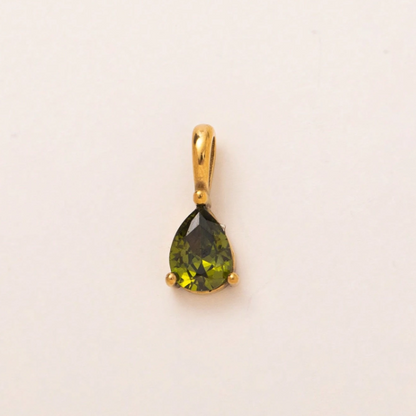 A gold pendant featuring a pear-shaped olive green gemstone in a prong setting, displayed on a plain off-white background.