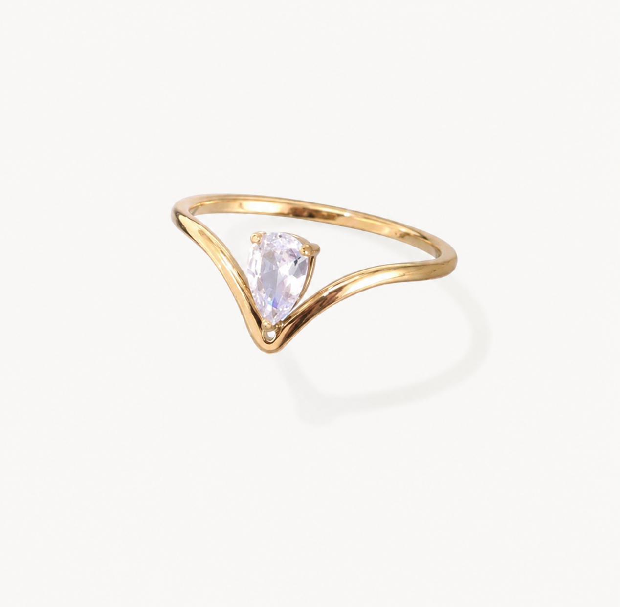 A gold ring with a curved, open V-shaped band and a central pear-cut clear gemstone, shown on a clean off-white background.
