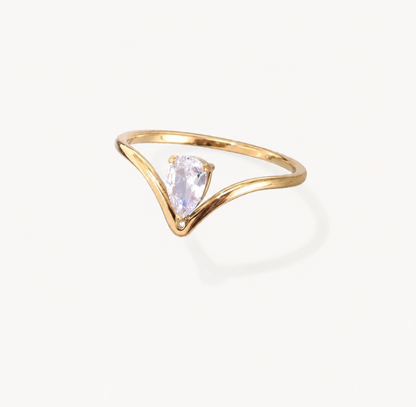A gold ring with a curved, open V-shaped band and a central pear-cut clear gemstone, shown on a clean off-white background.
