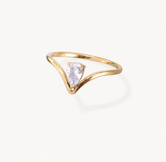 A gold ring with a curved, open V-shaped band and a central pear-cut clear gemstone, shown on a clean off-white background.