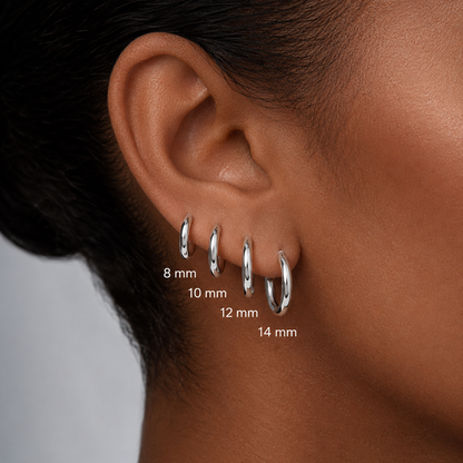 Close-up of a person's ear wearing four silver hoop earrings in different sizes labeled 8 mm, 10 mm, 12 mm, and 14 mm.