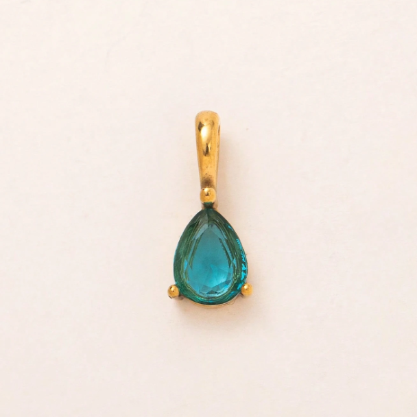 A gold pendant featuring a teardrop-shaped turquoise gemstone, set against a plain off-white background.