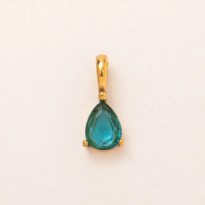 A gold pendant featuring a teardrop-shaped turquoise gemstone, set against a plain off-white background.