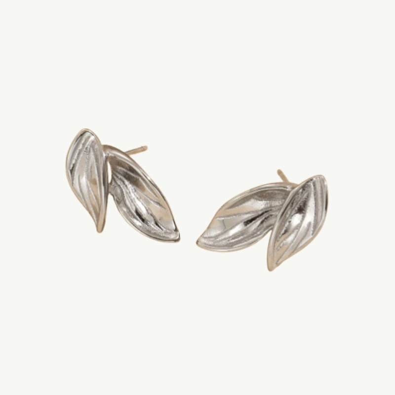 A pair of silver-toned leaf stud earrings with a textured, ribbed surface, displayed on a clean off-white background.