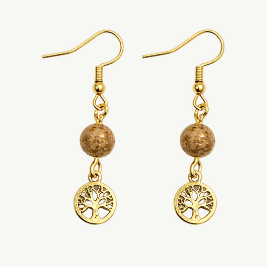 Gold earrings with tree of life charms on a white background